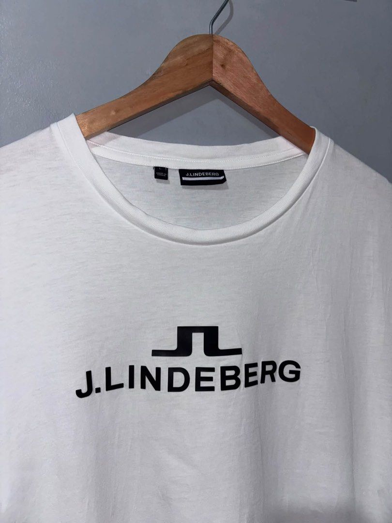 j.lindeberg White T-Shirt Size L (Category: Luxury Apparel) located in Cuyapo. Submitted by mn.finds (Listing ID 1468136745, Image 2). Description: - Brand: J.Lindeberg - Color: White with black chest logo print - Size: Large - Style: short sleeves - Origin: Made in China - Condition: Clean fabric overall, with minor fraying .