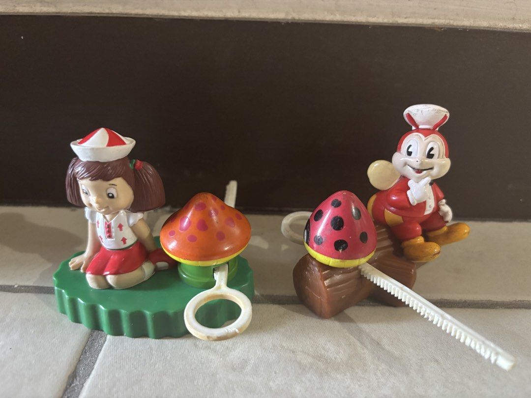Jolly Spin-Off (RARE AND VINTAGE ) (Category: Designer & Blind Box Toys) located in Paranaque City. Submitted by pengkit (Listing ID 1468152261, Image 1). Description: - Set of 2 classic Jollibee promotional toys: Jollibee and Hetty - Detailed designs: Hetty with an orange mushroom, Jollibee with a ladybug on a log - Includes original plastic pull-tab mechanisms on the base - Condition: Painted details with minor scuffs from display and storage -