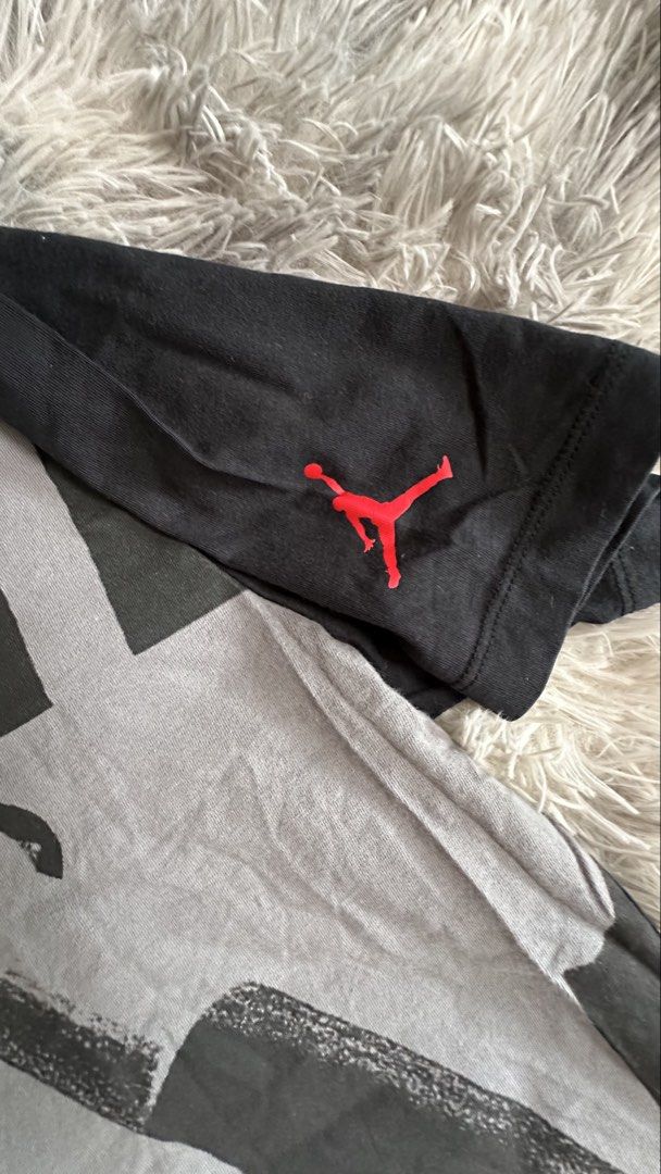 Jordan Graphic T-Shirt (Category: Tshirts & Polo Shirts ) located in Antipolo. Submitted by waco1313 (Listing ID 1468204718, Image 3). Description: - Brand: Jordan - Size: Medium - Design: Large Michael Jordan slam dunk graphic on the grey front panel with black sleeves - Details: Small red Jumpman logo on the left sleeve, classic crew neck - Material: 100% cotton, machine washable - Style: Standard fit, casual streetwear piece.