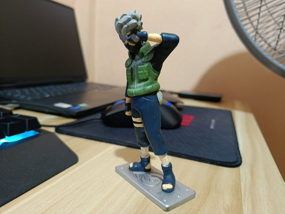 Kakashi Hatake Naruto Anime Figure Statue (Category: Figurines & Statues) located in Ligao. Submitted by travis40 (Listing ID 1468245739, Image 3). Description: - Kakashi Hatake figure from the popular anime series Naruto - Features iconic details: grey hair, green jonin vest, and blue outfit - Dynamic pose with hand raised near the forehead protector - Includes a grey rectangular base with an engraved Leaf Village symbol - Great addition to any 