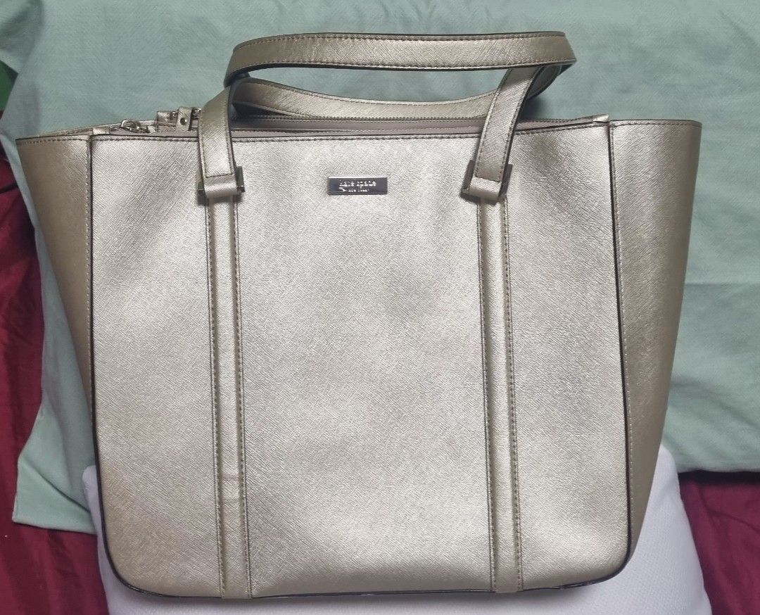 Kate Spade Gold Tote Bag (Category: Tote Bags) located in Manila. Submitted by ags028705 (Listing ID 1468191485, Image 1). Description: - Brand: Kate Spade - Material: Gold metallic leather - Style: Structured tote bag with front vertical strap detailing - Closure & Straps: Top zip closure with dual shoulder straps - Interior: Colorful multi-stripe fabric lining (pink, blue, red, brown, white) with an internal zippered pocket - Condition: Clean i