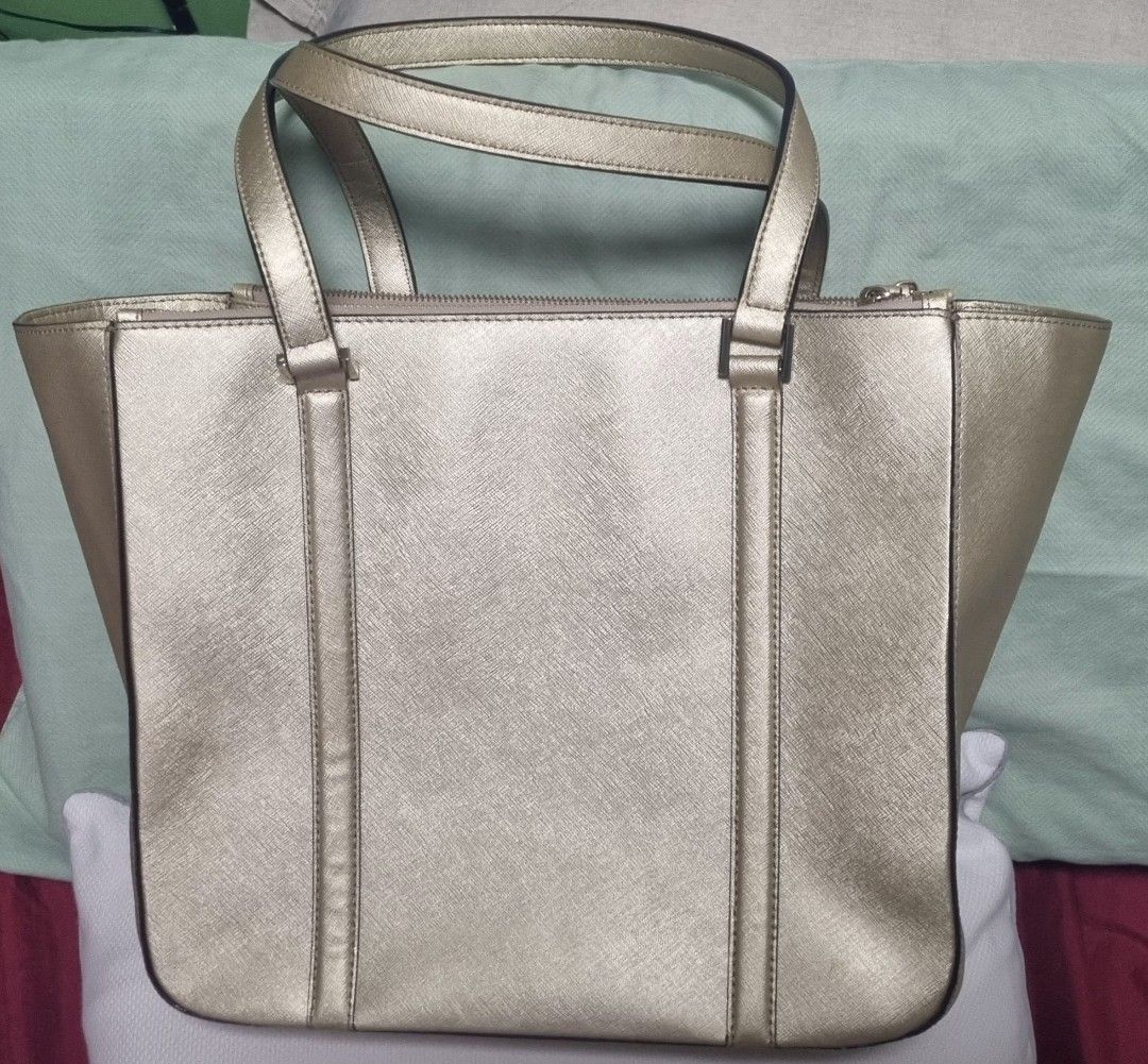 Kate Spade Gold Tote Bag (Category: Tote Bags) located in Manila. Submitted by ags028705 (Listing ID 1468191485, Image 3). Description: - Brand: Kate Spade - Material: Gold metallic leather - Style: Structured tote bag with front vertical strap detailing - Closure & Straps: Top zip closure with dual shoulder straps - Interior: Colorful multi-stripe fabric lining (pink, blue, red, brown, white) with an internal zippered pocket - Condition: Clean i