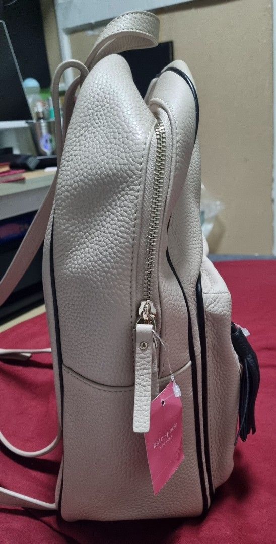 Kate Spade New York Leather Backpack (Category: Backpacks) located in Manila. Submitted by ags028705 (Listing ID 1468192324, Image 2). Description: - Brand: Kate Spade - Material: Soft beige pebbled leather with stylish black piping - Details: Front zipped pocket with a black tassel pull - Straps: Top handle and adjustable back straps for comfort - Condition: Brand new with store tags attached - Pls google for more detailed info on it. - COD is c