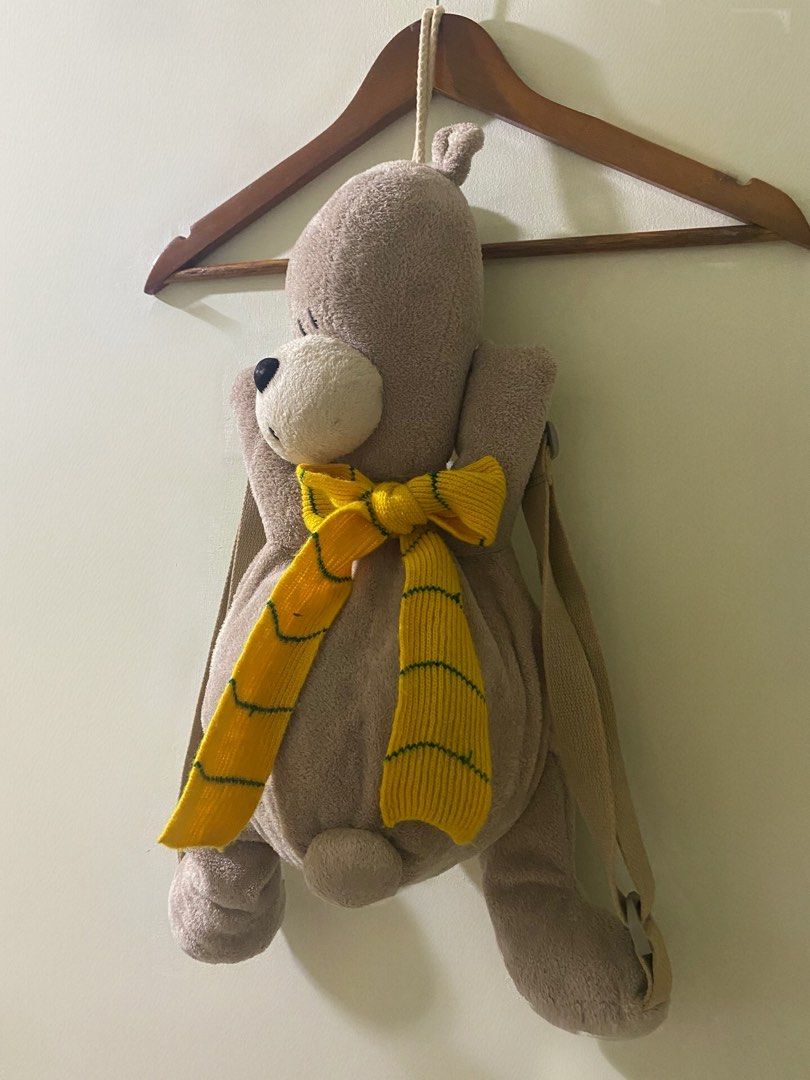 Kids Plush Teddy Bear Backpack- “Little Bubu” Bear (Category: Plushies & Soft Toys) located in Manila. Submitted by mturla4011142 (Listing ID 1468232313, Image 3). Description: Design: It’s a 3D teddy bear — the bear itself IS the bag. Light brown / greige fuzzy plush. Front: Bear face with big black nose, white muzzle, and a yellow striped knit scarf tied like a bowtie. On the belly it says “Little BuBu” embroidered in black. Back / Storage: The