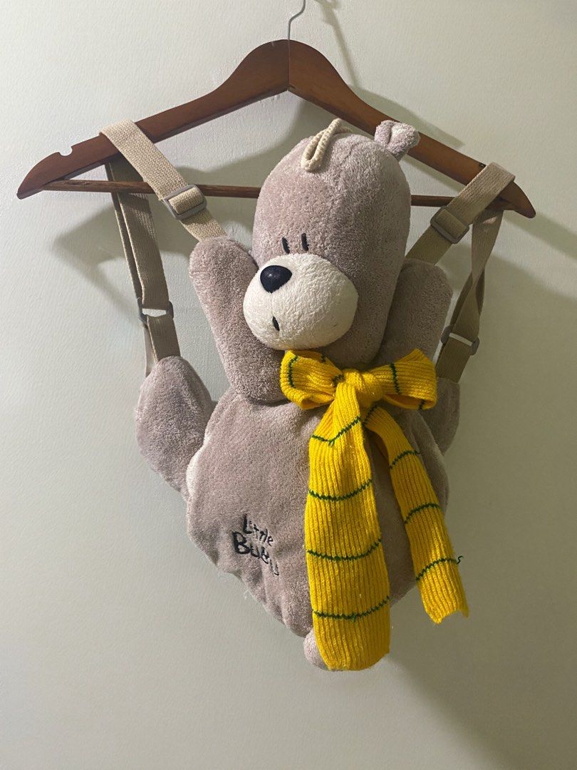 Kids Plush Teddy Bear Backpack- “Little Bubu” Bear (Category: Plushies & Soft Toys) located in Manila. Submitted by mturla4011142 (Listing ID 1468232313, Image 2). Description: Design: It’s a 3D teddy bear — the bear itself IS the bag. Light brown / greige fuzzy plush. Front: Bear face with big black nose, white muzzle, and a yellow striped knit scarf tied like a bowtie. On the belly it says “Little BuBu” embroidered in black. Back / Storage: The