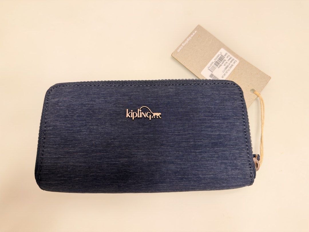 Kipling Alija Wallet Spark Navy (Category: Wallets & Card holders) located in Manila. Submitted by shopbureau (Listing ID 1468096504, Image 1). Description: - Brand: Kipling - Model: Alija Wallet - Color: Spark Navy (denim-like fabric) - Hardware: Rose gold metal Kipling logo - Closure: Zip-around with attached wrist strap - Interior: Multiple card slots, slip compartments, and zippered coin pocket - Condition: Brand new with original retail tag 