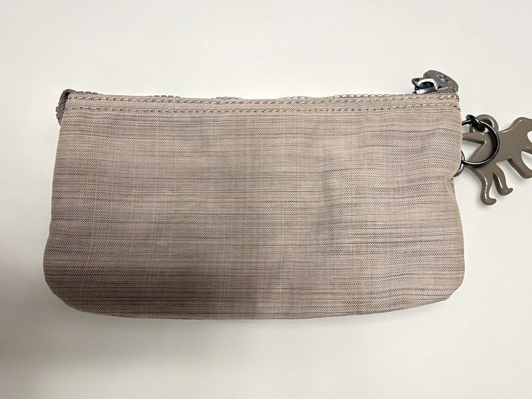 Kipling multi-compartment zip pouch with monkey keychain (Category: Purses & Pouches) located in Manila. Submitted by shopbureau (Listing ID 1468096424, Image 2). Description: - Authentic Kipling zipped pouch in a versatile neutral grey-brown textured fabric - Features the signature Kipling monkey keyring on the side loop - Multiple zippered sections and compartments lined with patterned fabric - Classic Kipling interior logo patch - Compact and 