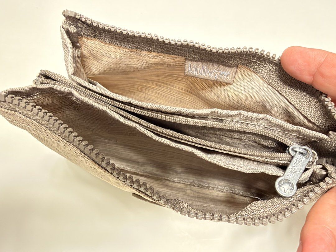Kipling multi-compartment zip pouch with monkey keychain (Category: Purses & Pouches) located in Manila. Submitted by shopbureau (Listing ID 1468096424, Image 3). Description: - Authentic Kipling zipped pouch in a versatile neutral grey-brown textured fabric - Features the signature Kipling monkey keyring on the side loop - Multiple zippered sections and compartments lined with patterned fabric - Classic Kipling interior logo patch - Compact and 