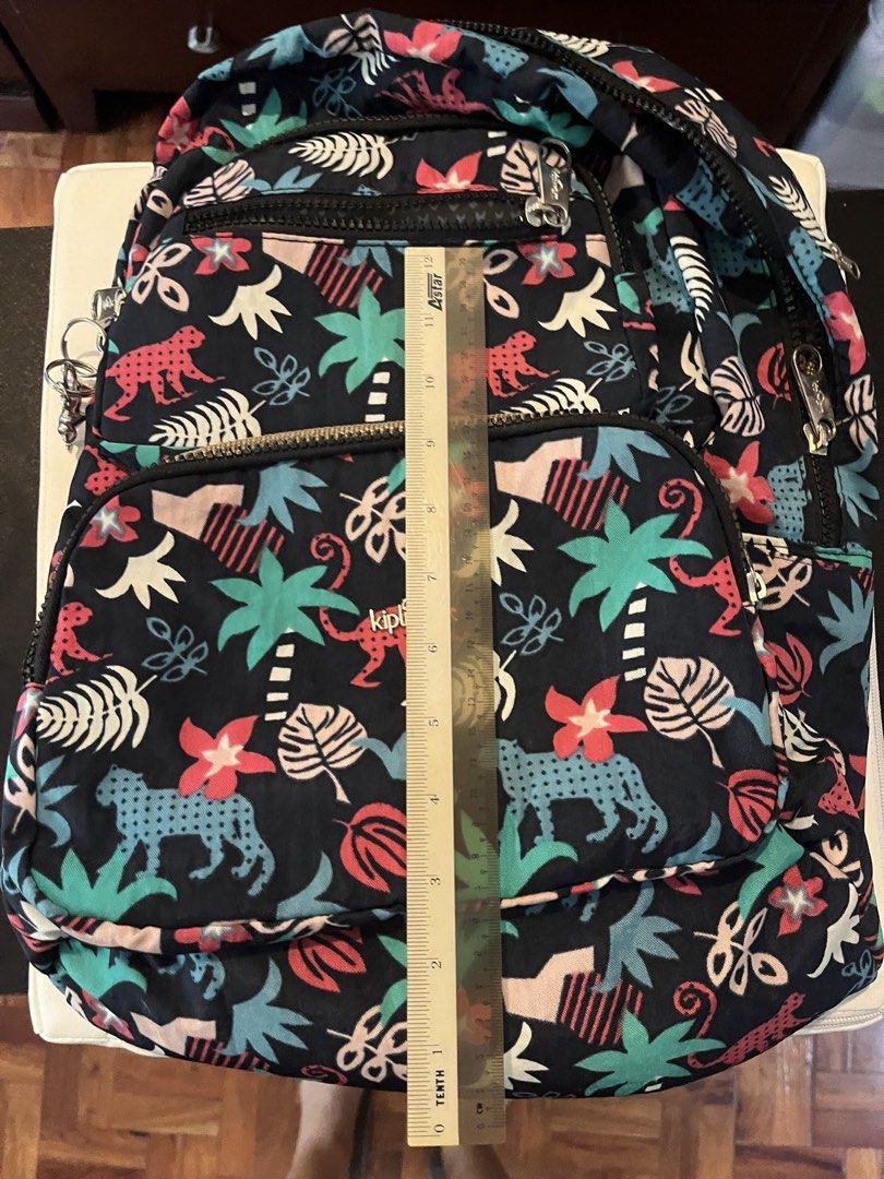 Kipling Tropical Jungle Print Backpack (Category: Backpacks) located in Paranaque City. Submitted by tingar08 (Listing ID 1468137919, Image 2). Description: - Brand: Kipling - Design: Dark blue with vibrant jungle print (pink monkeys, turquoise leopards, palm trees, and tropical flowers) - Compartments: Multiple zippered front pockets for easy organization - Measurements: Approx. 11" wide x 11.5" tall - Hardware: Sturdy zippers with durable metal