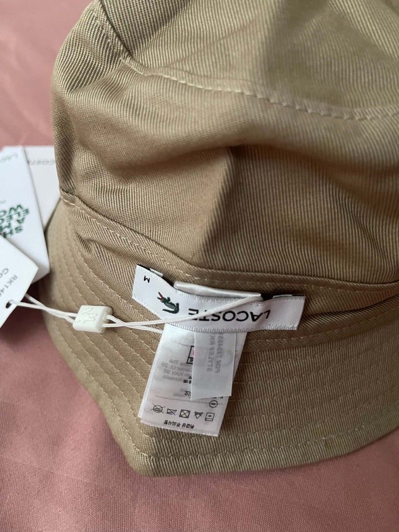 Lacoste Bucket Hat Beige Size M (Category: Caps & Hats) located in Cavite. Submitted by vastowl_7d1ce5 (Listing ID 1468145098, Image 2). Description: - Brand: Lacoste - Style: Bucket hat - Color: Beige - Size: M - Material: Classic twill fabric with stitched brim - Details: Green crocodile logo on inner label tag - Condition: Brand new, clean, with attached paper tags still on the cord.