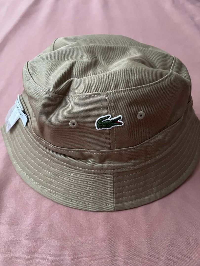 Lacoste Bucket Hat Beige Size M (Category: Caps & Hats) located in Cavite. Submitted by vastowl_7d1ce5 (Listing ID 1468145098, Image 1). Description: - Brand: Lacoste - Style: Bucket hat - Color: Beige - Size: M - Material: Classic twill fabric with stitched brim - Details: Green crocodile logo on inner label tag - Condition: Brand new, clean, with attached paper tags still on the cord.
