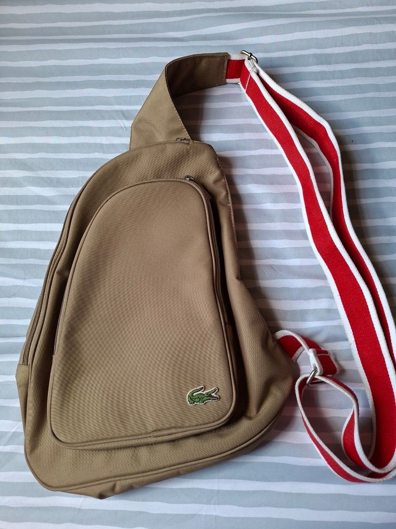 Lacoste Sling Bag Khaki with Red and White Strap (Category: Cross-body Bags) located in Binangonan. Submitted by anjiscloset (Listing ID 1468069679, Image 1). Description: - Brand: Lacoste - Color: Khaki with a bold red and white adjustable strap - Material: Durable canvas designed for daily wear - Design: Stylish teardrop shape featuring the signature embroidered crocodile logo - Compartments: Smooth-zippered main compartment and front zipped po
