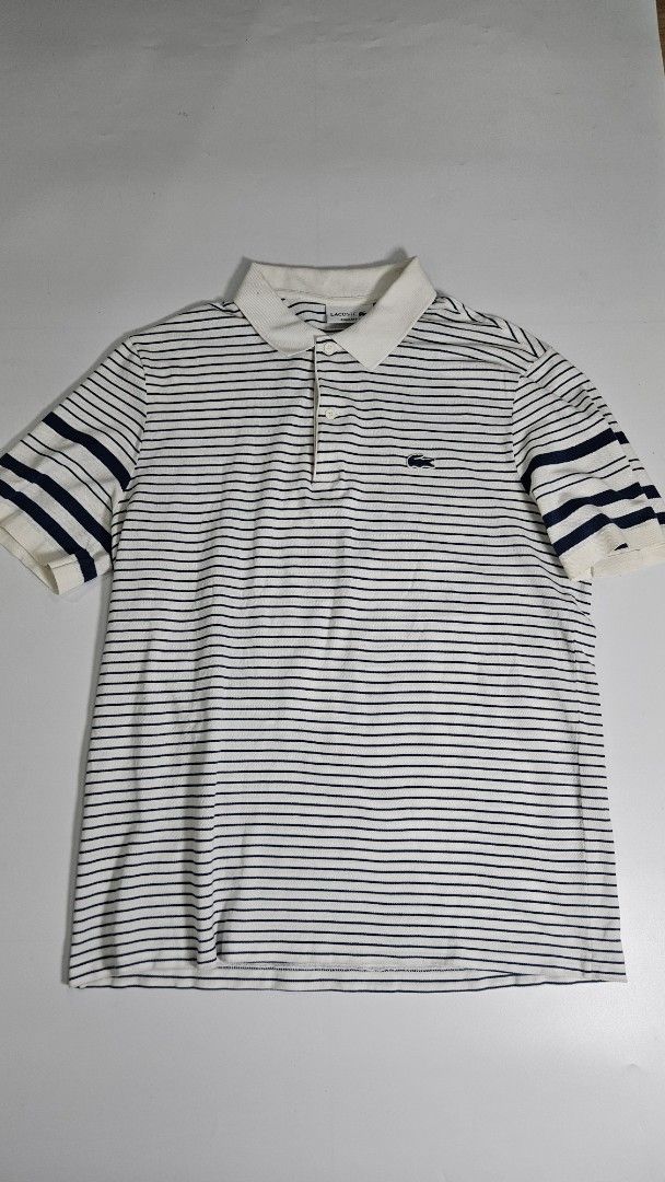 Lacoste Striped Regular Fit Polo Shirt (Category: Tshirts & Polo Shirts ) located in Alfonso. Submitted by jbcamet (Listing ID 1468192983, Image 1). Description: - Brand: Lacoste - Design: White and navy blue stripes with classic collar and two-button placket - Fit & Size: Regular fit, US L / French 5 - Material: 100% premium cotton (Made in Morocco) - Features: Short sleeves with banded cuffs and iconic embroidered crocodile logo on the chest - 