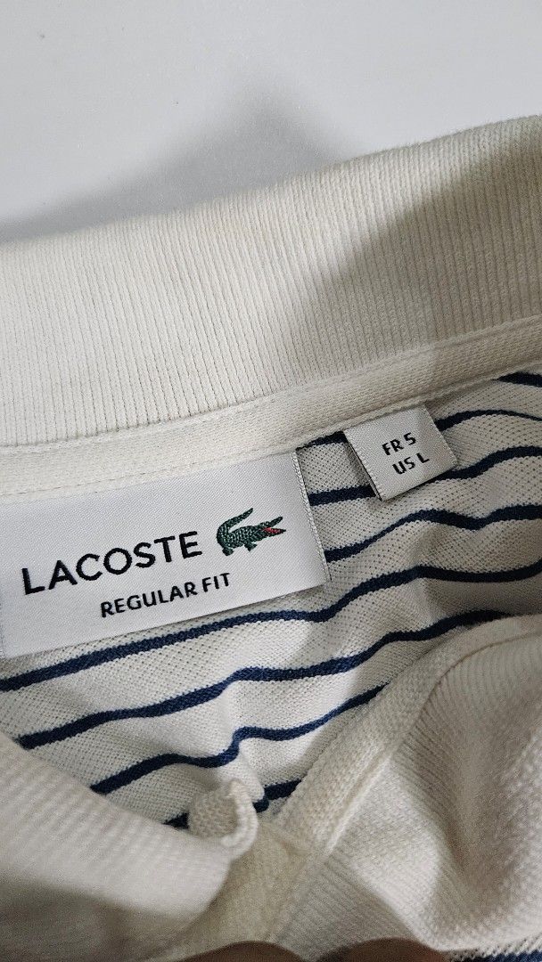 Lacoste Striped Regular Fit Polo Shirt (Category: Tshirts & Polo Shirts ) located in Alfonso. Submitted by jbcamet (Listing ID 1468192983, Image 2). Description: - Brand: Lacoste - Design: White and navy blue stripes with classic collar and two-button placket - Fit & Size: Regular fit, US L / French 5 - Material: 100% premium cotton (Made in Morocco) - Features: Short sleeves with banded cuffs and iconic embroidered crocodile logo on the chest - 