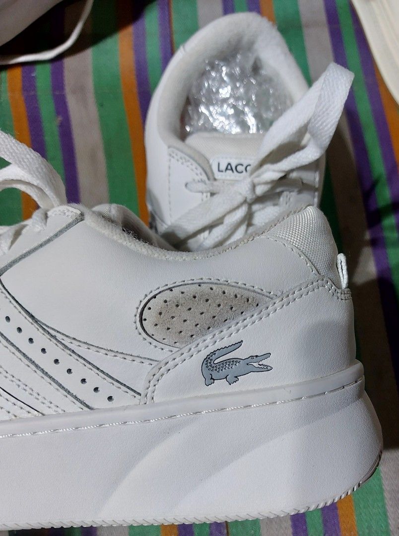 Lacoste White Sneakers (Category: Sneakers) located in Nabunturan. Submitted by creep012181 (Listing ID 1468209382, Image 2). Description: White Lacoste sneakers with classic crocodile logo on the side. Lace-up closure, chunky rubber sole, and perforated details on the toe and side panels. Clean white leather upper with matching laces. Comfortable everyday trainers with distinct branding on the tongue and heel area..