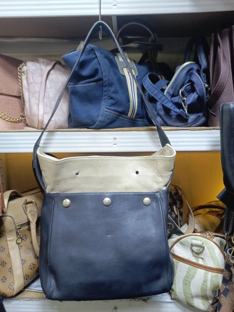 Lancel Leather Shoulder Bag Navy Cream (Category: Shoulder Bags) located in Manila. Submitted by del_thrifts03 (Listing ID 1468109165, Image 1). Description: - Authentic Lancel shoulder bag in a stylish navy blue and cream leather two-tone design - Features eye-catching gold-tone metal snaps on the front pocket - Equipped with a long strap for comfortable shoulder wear - Clean, structured shape with neat side seams - Practical, good everyday size