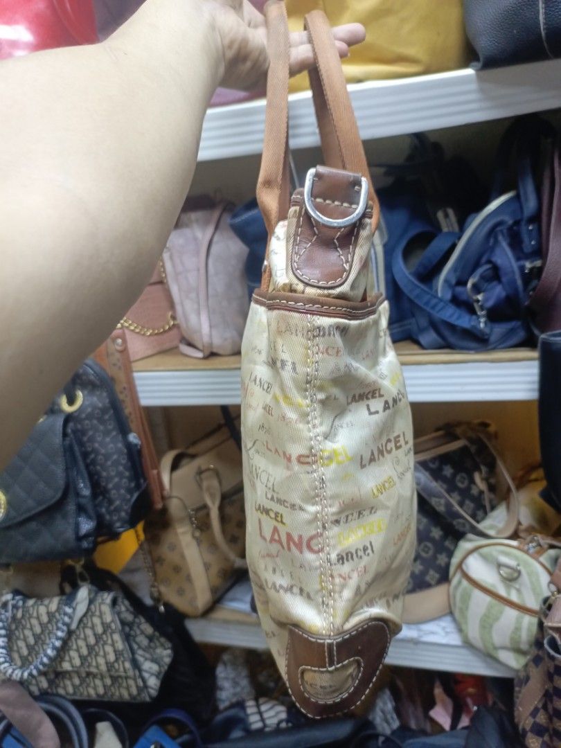 Lancel Paris 1876 Monogram Tote Bag (Category: Tote Bags) located in Manila. Submitted by del_thrifts03 (Listing ID 1468111526, Image 3). Description: - Brand: Lancel Paris (1876) - Style: Canvas tote bag with all-over multicolored logo print in beige - Material: Canvas body with brown leather trim and dual web handles - Closure: Top zip closure with branded hardware pull - Interior: Dark fabric lining with one inner zipped pocket and leather bra