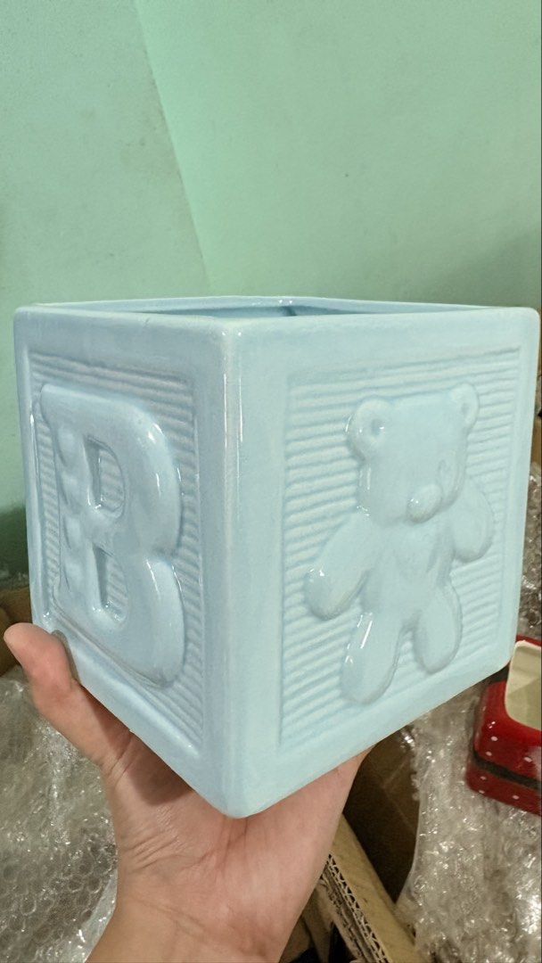 Light Blue Ceramic Baby Block planter/holder (Category: Other Home Decor) located in Quezon City. Submitted by ar.sulit.finds (Listing ID 1468257928, Image 1). Description: - Material: High-quality ceramic with a glossy finish - Design: Light blue block planter with a raised letter B on one side and a teddy bear on the other - Texture: Stylish ribbed borders with an open top and hollow interior - Versatility: Ideal as a small plant pot, succulent