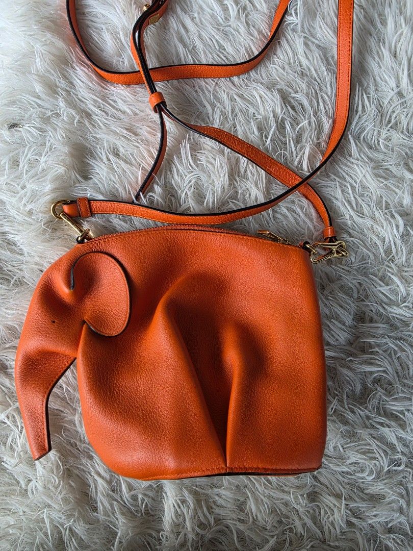 Loewe Orange Elephant Crossbody Bag (Category: Cross-body Bags) located in Lemery. Submitted by venus23 (Listing ID 1468221423, Image 2). Description: - Loewe elephant crossbody bag in a vibrant bright orange textured leather - Features iconic elephant design complete with ear and trunk details - Elegant gold-tone hardware with a secure zipper closure - Adjustable leather shoulder strap fitted with Loewe-stamped gold clasps - Clean pebbled leathe