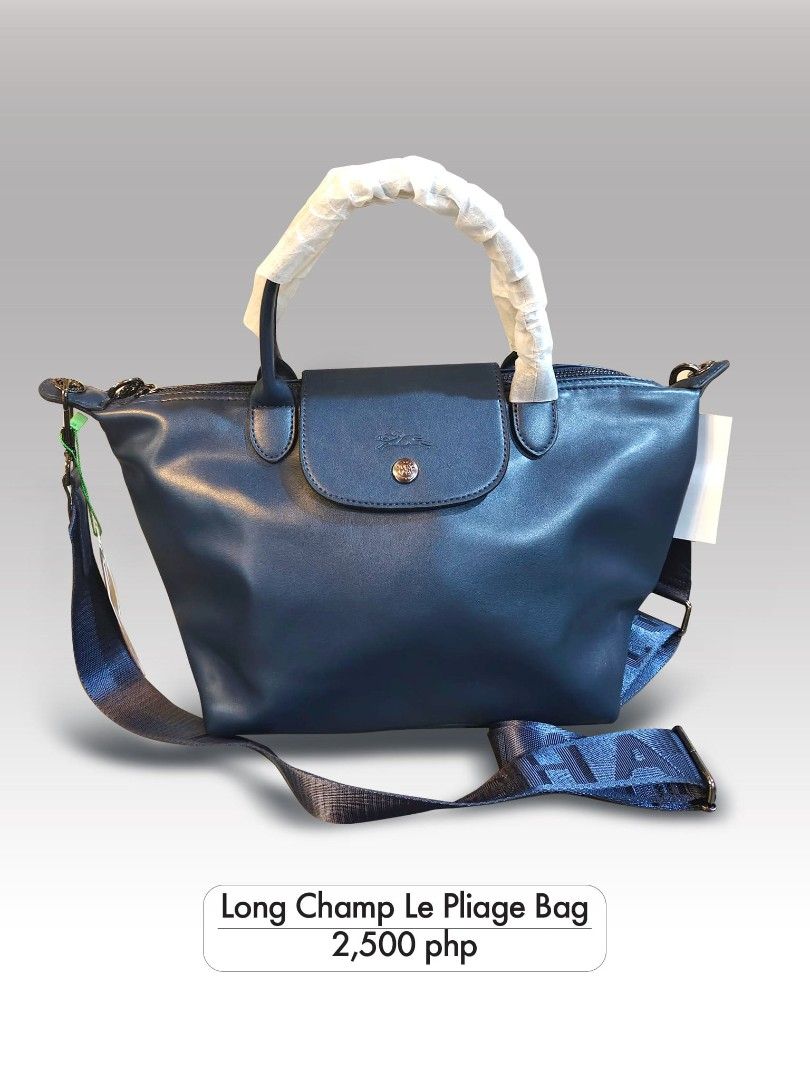 Long Champ Le Pliage Bag (Category: Luxury Bags & Wallets) located in Manila. Submitted by changsluxury (Listing ID 1468179860, Image 1). Description: - Brand: Longchamp Le Pliage - Color: Navy blue - Condition: Brand new, never used, packaging intact - Handles: Top handle style with protective wrapper still on - Strap: Includes detachable blue strap with bold lettering - Closure: Flap closure with metallic snap button - Details: White tag attach