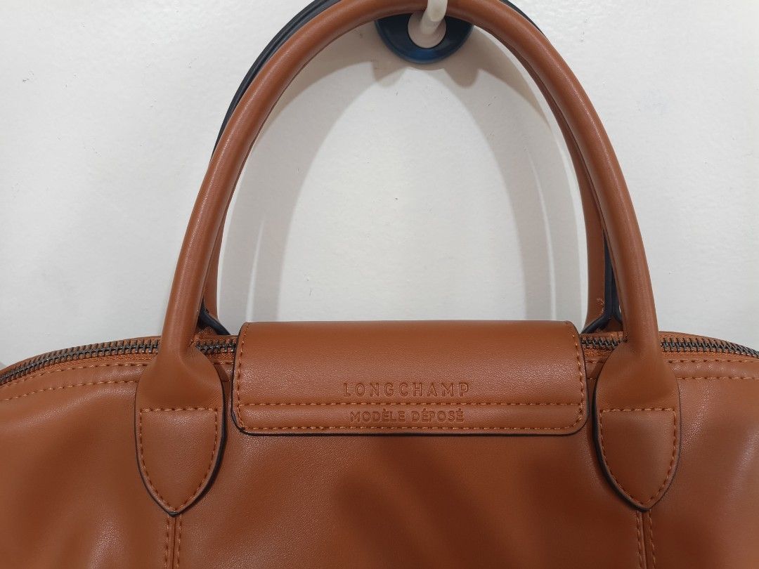 Longchamp Brown Leather Tote Handbag (Category: Luxury Bags & Wallets) located in Quezon City. Submitted by closeta38 (Listing ID 1465757307, Image 2). Description: - Authentic Longchamp tan leather handbag - Classic top handle design with flap and snap button closure - Features the iconic embossed horse logo on the front - Clean and elegant stitching along the front panels - Condition is well-maintained and ready to use - With extra strap, shoul