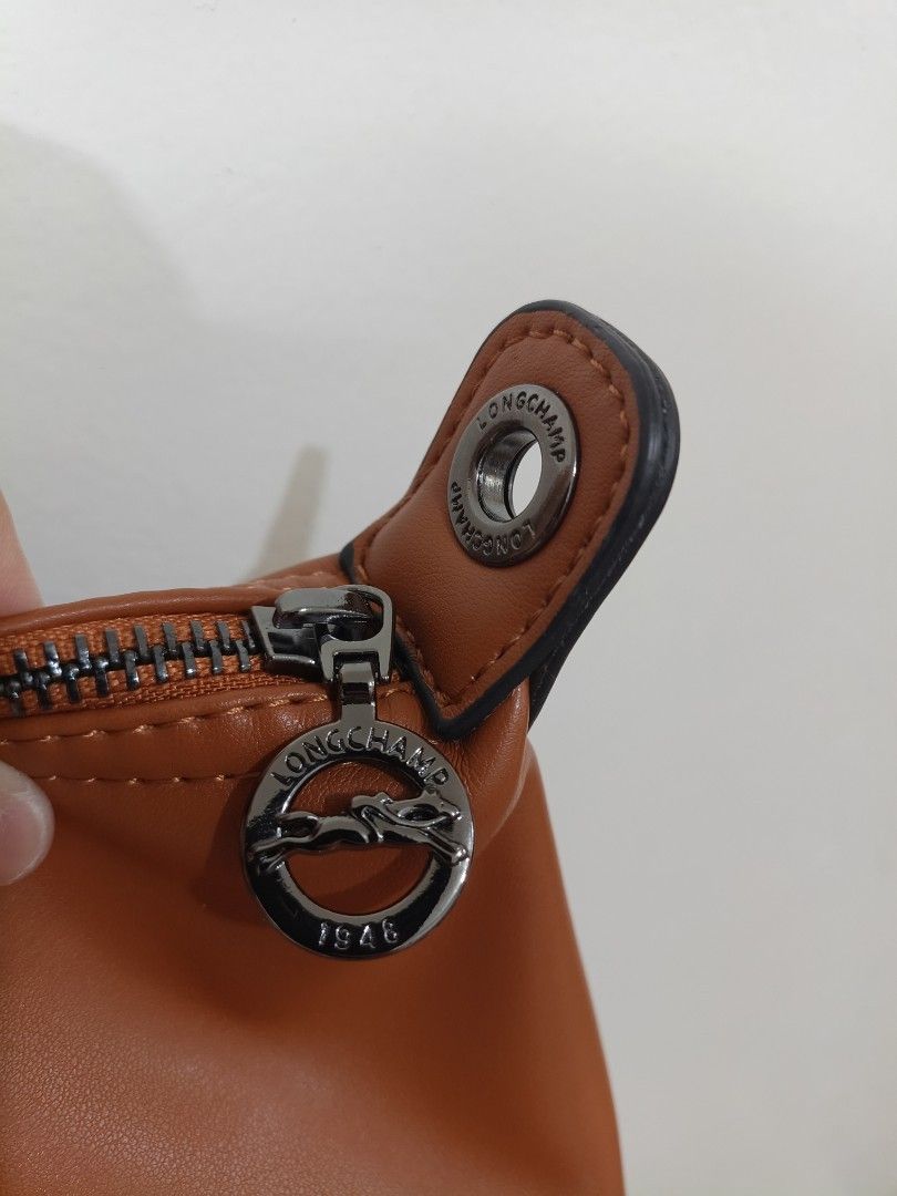Longchamp Brown Leather Tote Handbag (Category: Luxury Bags & Wallets) located in Quezon City. Submitted by closeta38 (Listing ID 1465757307, Image 3). Description: - Authentic Longchamp tan leather handbag - Classic top handle design with flap and snap button closure - Features the iconic embossed horse logo on the front - Clean and elegant stitching along the front panels - Condition is well-maintained and ready to use - With extra strap, shoul
