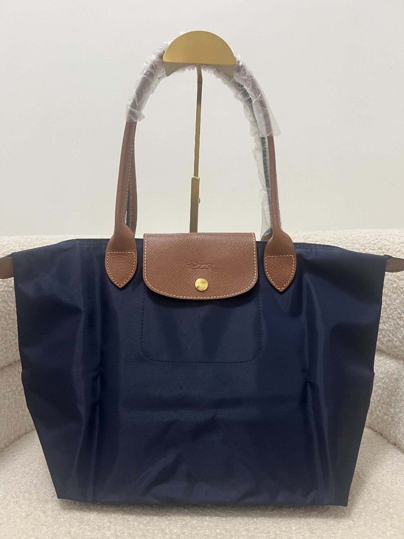Longchamp Le Pliage Tote Bag Navy Blue (Category: Tote Bags) located in Paoay. Submitted by rvf1230 (Listing ID 1468072298, Image 2). Description: - Brand: Longchamp Le Pliage Club - Color: Navy blue with brown leather flap and handles - Condition: Brand new, unworn, handles still wrapped in plastic - Material: Durable nylon body with gold-tone hardware and embossed horse logo - Features: Spacious interior, perfect for daily essentials.