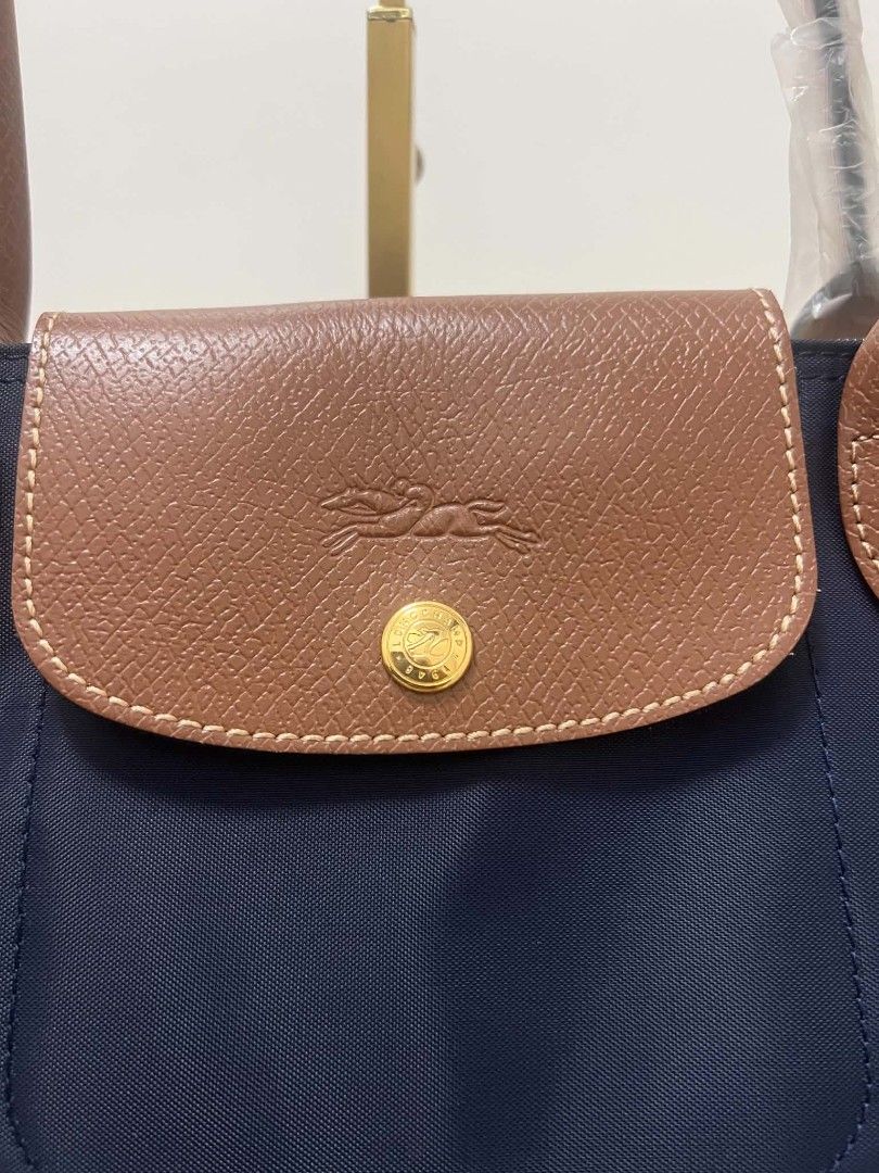 Longchamp Le Pliage Tote Bag Navy Blue (Category: Tote Bags) located in Paoay. Submitted by rvf1230 (Listing ID 1468072298, Image 3). Description: - Brand: Longchamp Le Pliage Club - Color: Navy blue with brown leather flap and handles - Condition: Brand new, unworn, handles still wrapped in plastic - Material: Durable nylon body with gold-tone hardware and embossed horse logo - Features: Spacious interior, perfect for daily essentials.