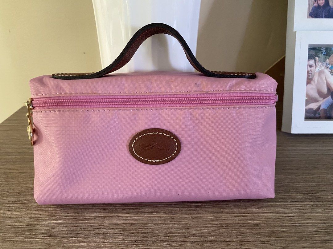 Longchamp Pink Cosmetic Pouch (Category: Purses & Pouches) located in Santa Rosa. Submitted by hoardqueensdeclutter (Listing ID 1468197507, Image 2). Description: - Authentic Longchamp cosmetic pouch in soft pink nylon - Features a brown leather handle and gold-tone zip pull with oval logo patch - Smooth-running zipper - Interior has noticeable ink stains and cosmetic marks from previous use - Great and functional piece for everyday use at a budg