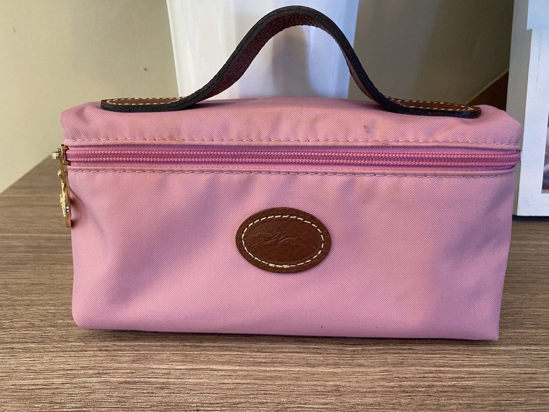 Longchamp Pink Cosmetic Pouch (Category: Purses & Pouches) located in Santa Rosa. Submitted by hoardqueensdeclutter (Listing ID 1468197507, Image 1). Description: - Authentic Longchamp cosmetic pouch in soft pink nylon - Features a brown leather handle and gold-tone zip pull with oval logo patch - Smooth-running zipper - Interior has noticeable ink stains and cosmetic marks from previous use - Great and functional piece for everyday use at a budg