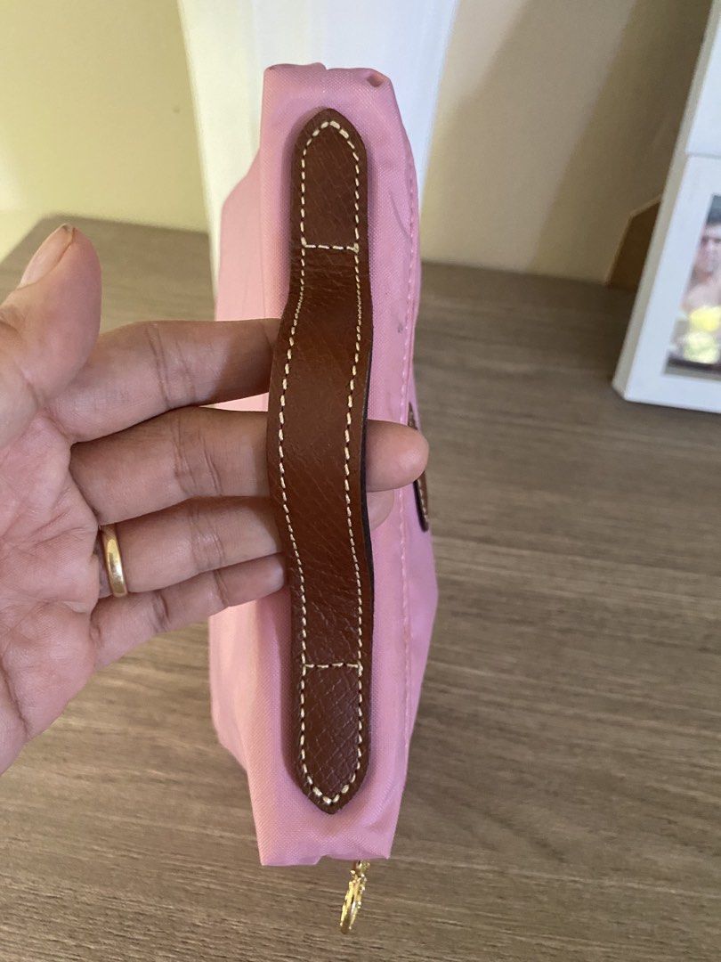 Longchamp Pink Cosmetic Pouch (Category: Purses & Pouches) located in Santa Rosa. Submitted by hoardqueensdeclutter (Listing ID 1468197507, Image 3). Description: - Authentic Longchamp cosmetic pouch in soft pink nylon - Features a brown leather handle and gold-tone zip pull with oval logo patch - Smooth-running zipper - Interior has noticeable ink stains and cosmetic marks from previous use - Great and functional piece for everyday use at a budg