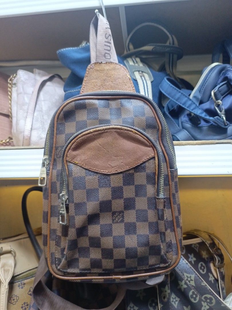 Louis Vuitton Damier Ebene Sling Bag (Category: Luxury Bags & Wallets) located in Manila. Submitted by del_thrifts03 (Listing ID 1468111132, Image 1). Description: - Stylish brown checkerboard pattern - Premium tan leather accent patch on front pocket and top handle - Comfortable branded fabric strap with adjustable metal buckle - Secure zip closure with engraved metal puller - Compact size, perfect for daily wear and essentials.