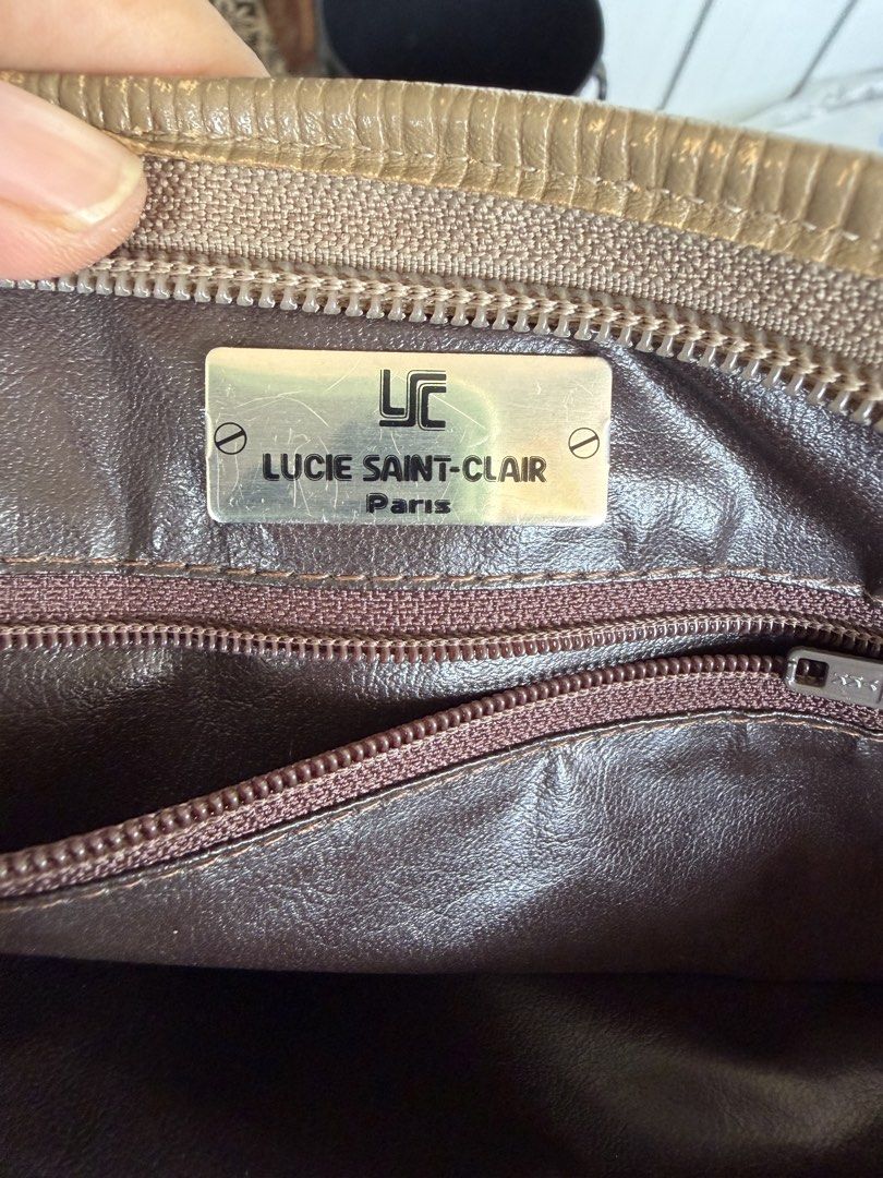 Lucie Saint-Clair Paris patterned clutch handbag (Category: Clutches) located in Digos. Submitted by old_soul. (Listing ID 1468101595, Image 3). Description: - Brand: Lucie Saint-Clair Paris - Style: Clutch bag - Color: Brown and tan - Material: Geometric patterned fabric with leather flaps and trim - Closure: Magnetic snap button on the front flap - Interior: Brown lining with a zippered pocket and metal designer logo plaque - Condition: Excelle