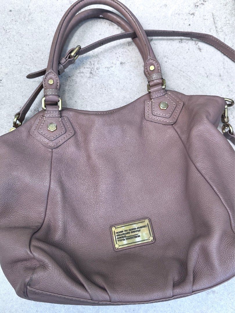 Marc by Marc Jacobs Leather Handbag (Category: Luxury Bags & Wallets) located in Quezon City. Submitted by gorjuspots (Listing ID 1468101636, Image 1). Description: - Brand: Marc by Marc Jacobs - Material: Taupe pebbled leather with gentle softening from use - Hardware: Gold-tone throughout with front logo plaque - Closure: Zip-closure main compartment with magnetic snap side buttons - Interior: Black and white logo fabric lining with zip and sli