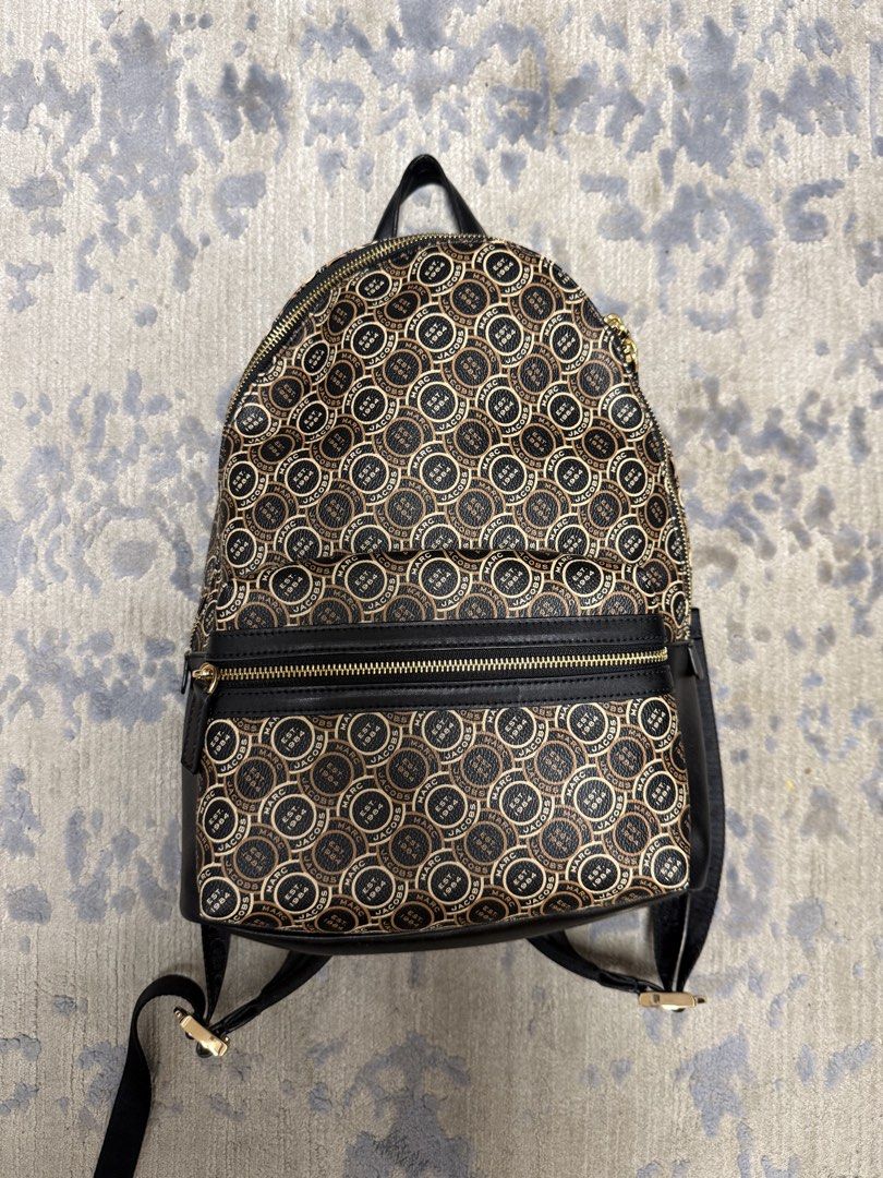 Marc Jacobs Monogram Pattern Backpack （分類：手袋及銀包）位於 Hong Kong。 由 thriphthingsz 提交（商品編號 1468078475，圖片 1）。簡介： Marc Jacobs monogram print backpack in black and beige. All-over circle logo pattern with EST 1984 text. Front zippered pocket, dual adjustable webbing straps featuring printed Marc Jacobs branding in white text. Gold-tone hardware throughout. Black canvas back panel and base. Top handle attached. Clean condition inside and out.。