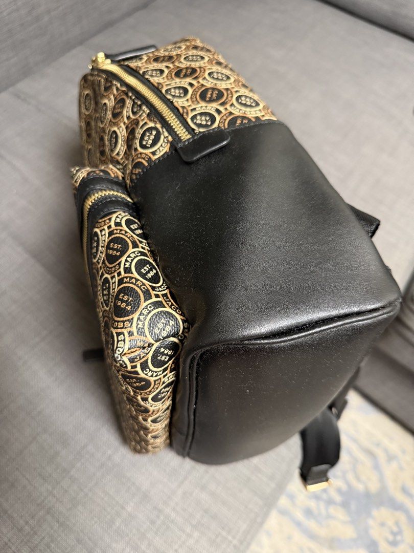 Marc Jacobs Monogram Pattern Backpack （分類：手袋及銀包）位於 Hong Kong。 由 thriphthingsz 提交（商品編號 1468078475，圖片 3）。簡介： Marc Jacobs monogram print backpack in black and beige. All-over circle logo pattern with EST 1984 text. Front zippered pocket, dual adjustable webbing straps featuring printed Marc Jacobs branding in white text. Gold-tone hardware throughout. Black canvas back panel and base. Top handle attached. Clean condition inside and out.。