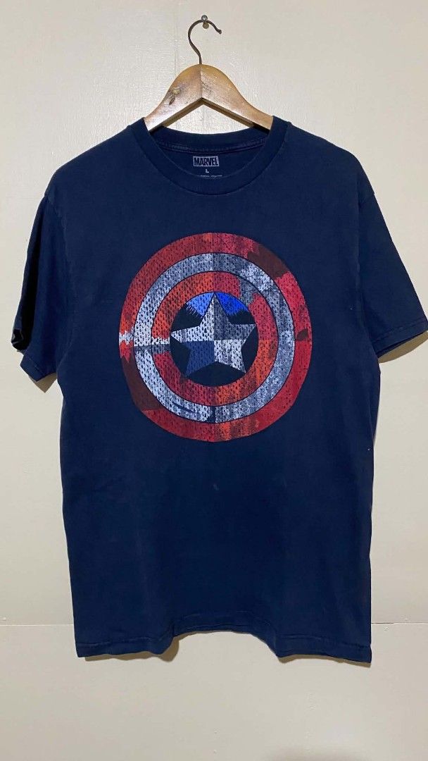 Marvel Captain America Shield T-Shirt (Category: Tshirts & Polo Shirts ) located in Bulacan. Submitted by rondeez (Listing ID 1468162271, Image 1). Description: - Official Marvel merchandise - Dark blue graphic tee with distressed Captain America shield print - Size: Large (tag printed inside collar) - Material: Comfortable cotton - Fit: Regular crew neck with short sleeves - Condition: Great addition for any Marvel fan.