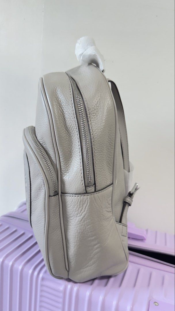 Michael Kors Grey Leather Backpack (Category: Backpacks) located in Quezon City. Submitted by dendionlineshop (Listing ID 1468144634, Image 2). Description: - Brand: Michael Kors - Material: Premium grey pebble leather - Design: Large debossed round logo patch on front zip pocket - Closure: Double zip closure on main compartment - Straps: Adjustable leather shoulder straps and top carry handle (top handle still wrapped in protective paper) - Cond