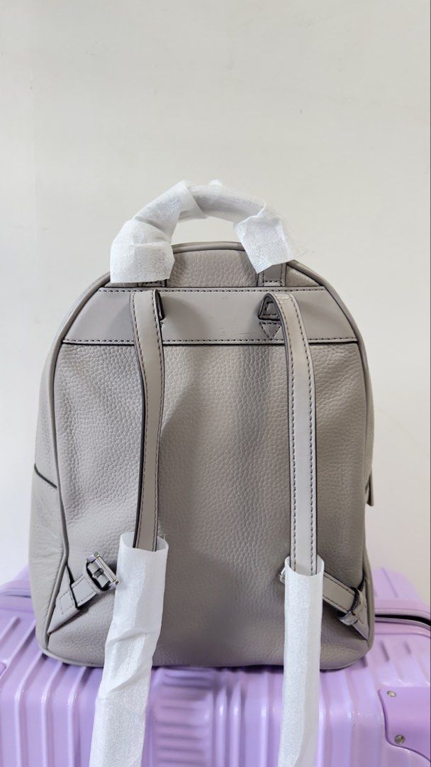 Michael Kors Grey Leather Backpack (Category: Backpacks) located in Quezon City. Submitted by dendionlineshop (Listing ID 1468144634, Image 3). Description: - Brand: Michael Kors - Material: Premium grey pebble leather - Design: Large debossed round logo patch on front zip pocket - Closure: Double zip closure on main compartment - Straps: Adjustable leather shoulder straps and top carry handle (top handle still wrapped in protective paper) - Cond