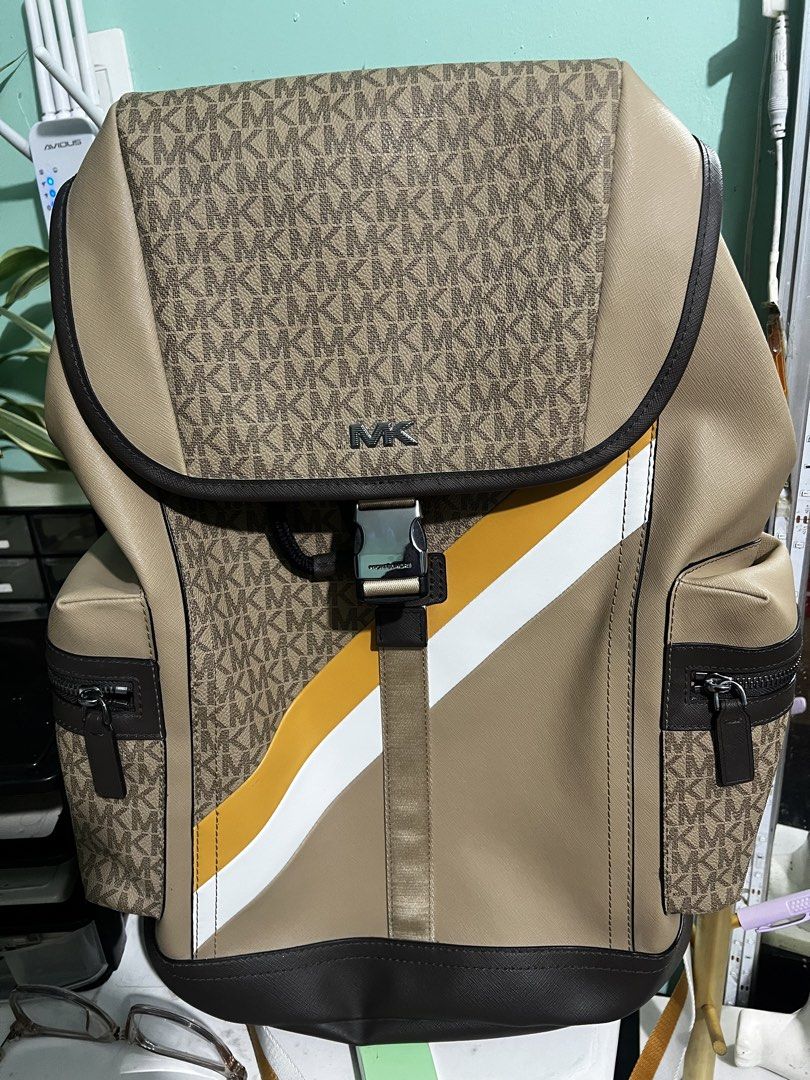 Michael Kors Signature Logo Stripe Flap Backpack (Category: Luxury Bags & Wallets) located in Manila. Submitted by cleverstone_21f597 (Listing ID 1468282302, Image 1). Description: - Authentic Michael Kors backpack in tan and brown monogram - Eye-catching diagonal yellow and white stripe across the front - Flap closure with a stylish buckle accent - Convenient side zip pockets for easy access - Adjustable shoulder straps with a breathable padded 