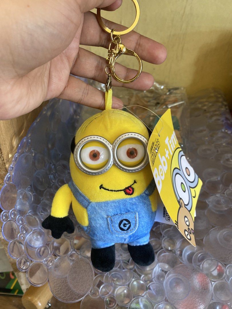 Minions Bob + Tim Plush Keychain (Category: Plushies & Soft Toys) located in Baguio. Submitted by thrift_bonita (Listing ID 1468147549, Image 2). Description: - Authentic Illumination Minions plush keychain - Features Bob with a cute sticking-out tongue and Tim bear tag - Wears blue denim-style overalls with the 'G' logo pocket - Detailed with black gloves, boots, and plastic goggles - Includes a sturdy gold-tone keyring - Brand new with original