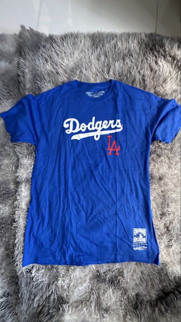Mitchell & Ness LA Dodgers Cooperstown Collection T-Shirt (Category: Tshirts & Polo Shirts ) located in Antipolo. Submitted by waco1313 (Listing ID 1468204511, Image 1). Description: - Brand: Mitchell & Ness (Cooperstown Collection) - Team: Los Angeles Dodgers - Color: Bright blue with red details - Design: Classic cursive Dodgers script with interlocking LA logo - Details: Official printed jock tag near hem, branded neck tag - Fit: Relaxed, soft