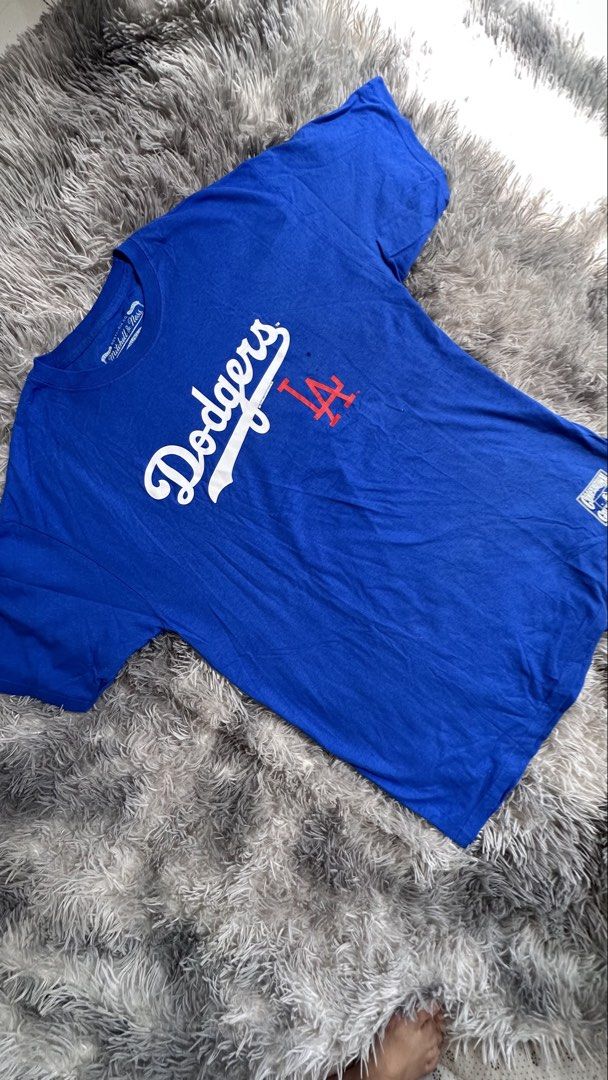 Mitchell & Ness LA Dodgers Cooperstown Collection T-Shirt (Category: Tshirts & Polo Shirts ) located in Antipolo. Submitted by waco1313 (Listing ID 1468204511, Image 2). Description: - Brand: Mitchell & Ness (Cooperstown Collection) - Team: Los Angeles Dodgers - Color: Bright blue with red details - Design: Classic cursive Dodgers script with interlocking LA logo - Details: Official printed jock tag near hem, branded neck tag - Fit: Relaxed, soft