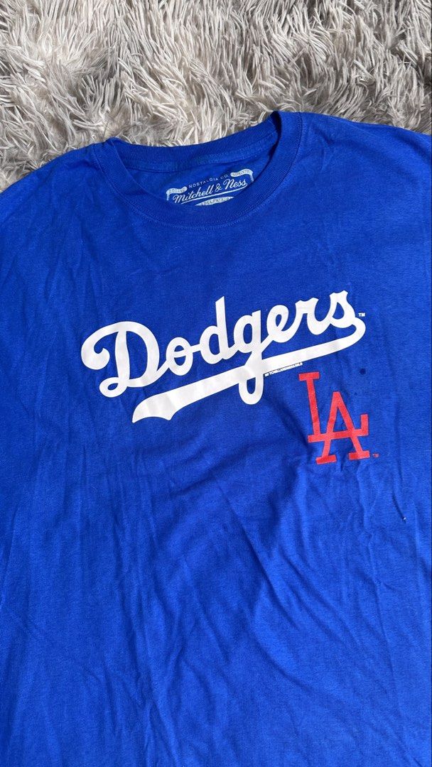 Mitchell & Ness LA Dodgers Cooperstown Collection T-Shirt (Category: Tshirts & Polo Shirts ) located in Antipolo. Submitted by waco1313 (Listing ID 1468204511, Image 3). Description: - Brand: Mitchell & Ness (Cooperstown Collection) - Team: Los Angeles Dodgers - Color: Bright blue with red details - Design: Classic cursive Dodgers script with interlocking LA logo - Details: Official printed jock tag near hem, branded neck tag - Fit: Relaxed, soft