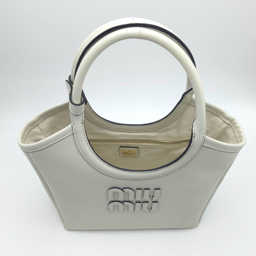 Miu Miu Ivy Top Handle Bag Off White (Category: Luxury Bags & Wallets) located in Cebu City. Submitted by affordabagss (Listing ID 1468100597, Image 2). Description: Miu Miu Ivy top handle bag crafted in smooth calfskin leather in a soft off-white shade with gold-tone hardware. Features the signature raised Miu Miu lettering logo, rounded leather top handles, and detachable adjustable leather shoulder strap. Finished with a structured tote-inspir