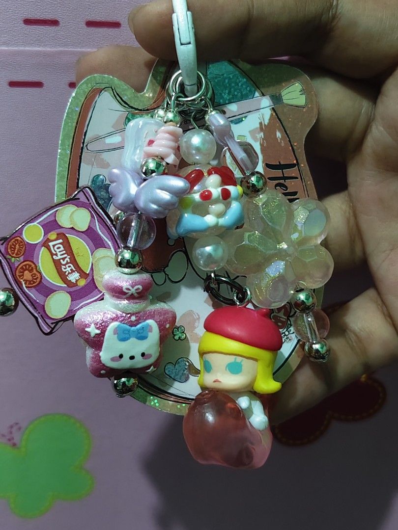 Molly Charms Keychain (Category: Charms) located in Rizal. Submitted by yves1211 (Listing ID 1468258727, Image 2). Description: - Adorable Molly 3D Keychain with multiple charms - Includes a pink Lay's chip bag, pastel angel wings, and a glittery flower accent - Silver-toned hardware with a secure white clasp clip - Great accessory for keys, bags, or backpacks - Adds a fun, personalized touch to your daily items.