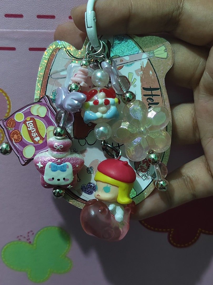 Molly Charms Keychain (Category: Charms) located in Rizal. Submitted by yves1211 (Listing ID 1468258727, Image 3). Description: - Adorable Molly 3D Keychain with multiple charms - Includes a pink Lay's chip bag, pastel angel wings, and a glittery flower accent - Silver-toned hardware with a secure white clasp clip - Great accessory for keys, bags, or backpacks - Adds a fun, personalized touch to your daily items.