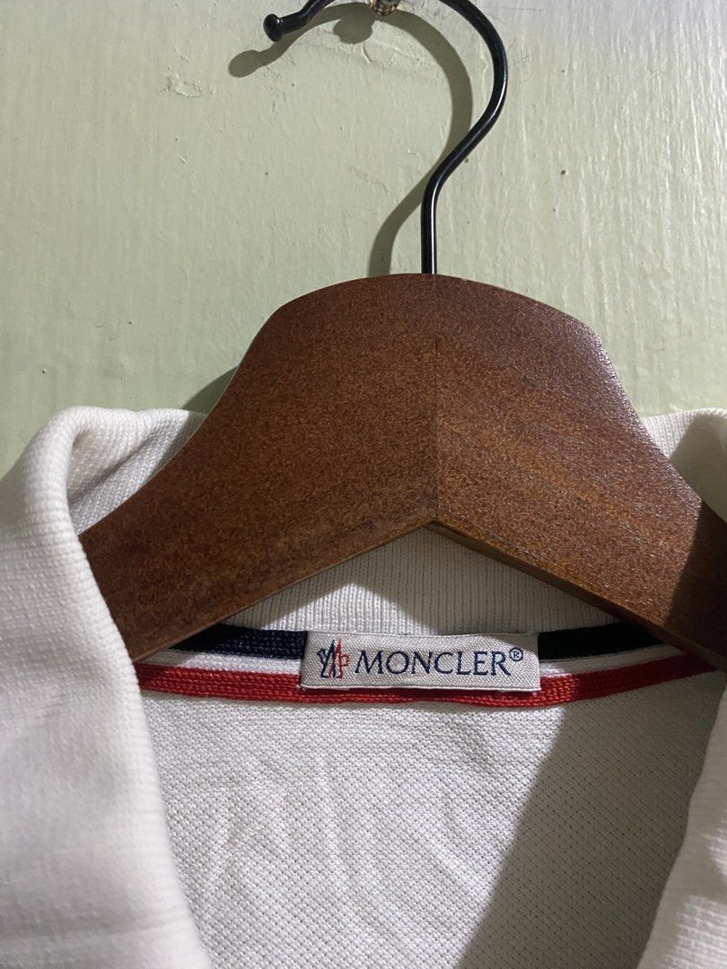Moncler White Polo Shirt Size M (Category: Tshirts & Polo Shirts ) located in Pandi. Submitted by nasya_thrift_collection2023 (Listing ID 1468235231, Image 2). Description: - Brand: Moncler - check detailed photo for issue - Item: Polo Shirt - Color: White with Red, White, and Navy Striped Tipping - Size: Medium (M) - Material: Premium Cotton Pique - Details: Classic collar, iconic Moncler logo badge on chest, 3-button placket - Condition: Excell