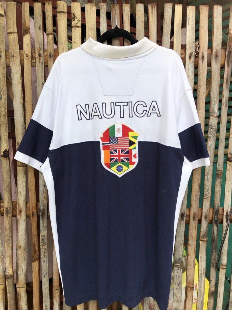 Nautica polo (Category: Tshirts & Polo Shirts ) located in Santa Catalina. Submitted by marlonsecondclosett (Listing ID 1468098141, Image 2). Description: vintage Nautica colorblock short-sleeve polo shirt featuring a white upper half, a navy blue lower half, the “NAUTICA” brand name printed across the back, and a multi-flag shield crest emblem. need wash .
