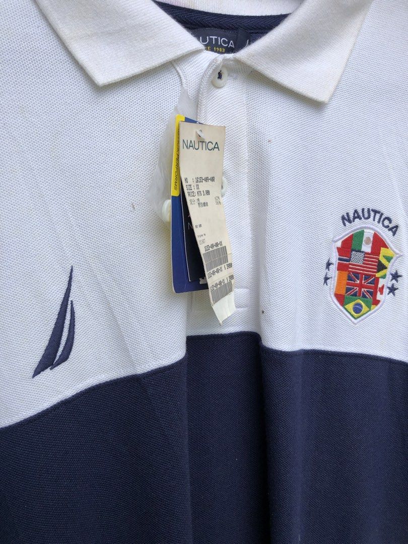 Nautica polo (Category: Tshirts & Polo Shirts ) located in Santa Catalina. Submitted by marlonsecondclosett (Listing ID 1468098141, Image 3). Description: vintage Nautica colorblock short-sleeve polo shirt featuring a white upper half, a navy blue lower half, the “NAUTICA” brand name printed across the back, and a multi-flag shield crest emblem. need wash .